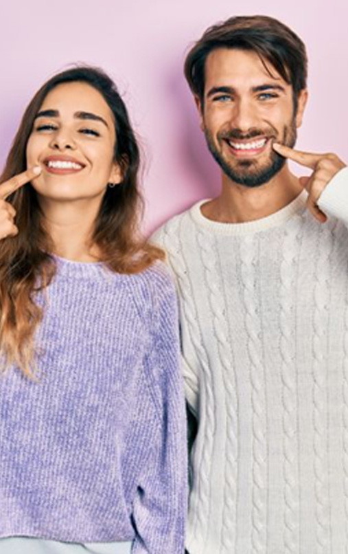 Happy young couple pointing at their teeth