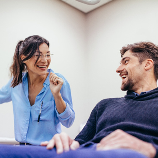 Female dentist and male patient smiling