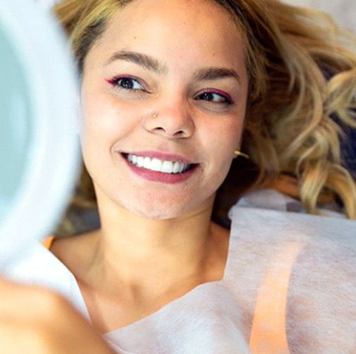 Cosmetic dentistry patient using mirror to admire her treatment results